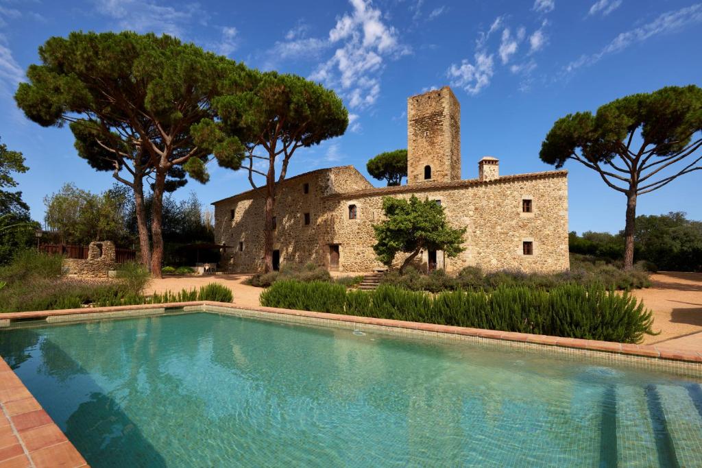 un edificio antiguo con una piscina frente a él en Masia Torre Lloreta S.XIII, en Calonge