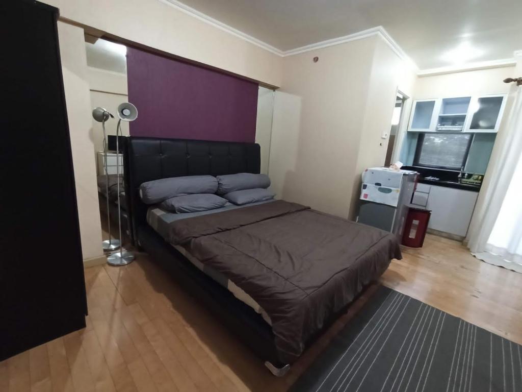 een slaapkamer met een groot bed met een paars hoofdeinde bij Ov Room in Jakarta