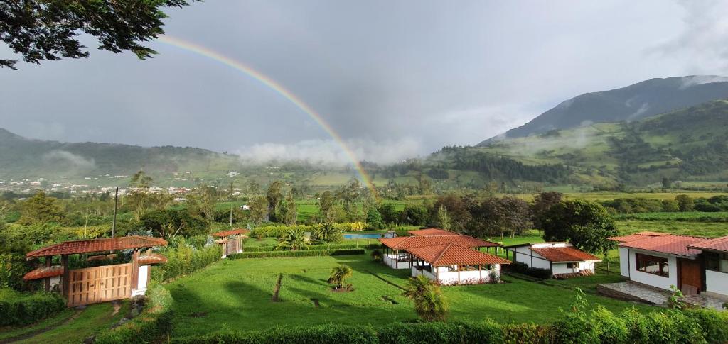 un arcobaleno sopra un villaggio con un campo verde e case di Eco Avocado Lodge a San José de Minas