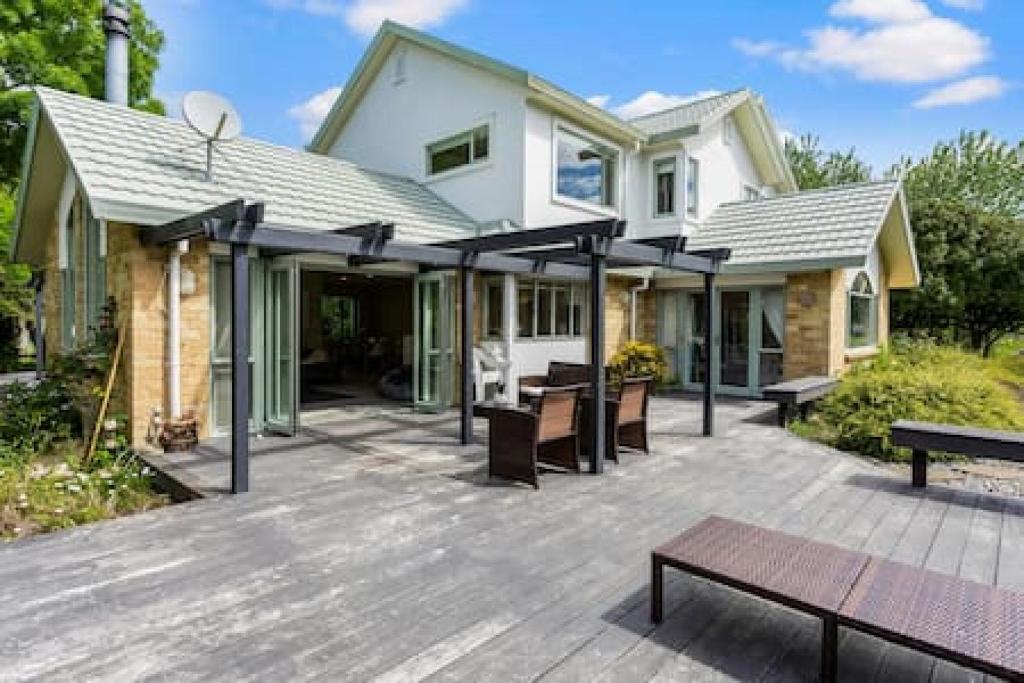 a house with a wooden deck with a patio at Nature Serenity Getaway with pool - deck - gardens in Auckland