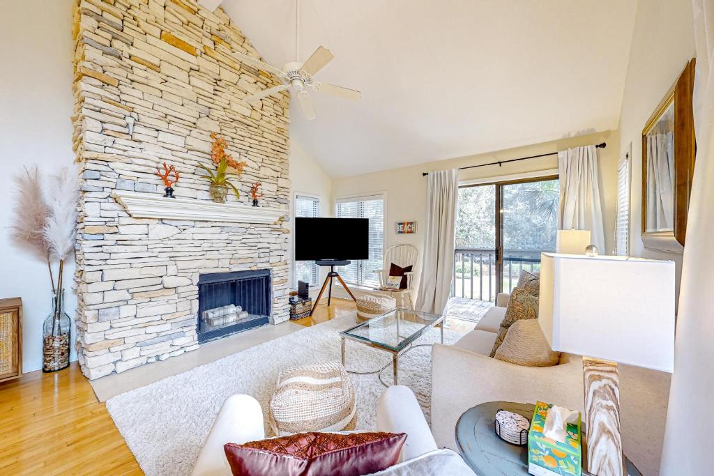 a living room with a stone fireplace and a tv at Parkside 4518 in Kiawah Island