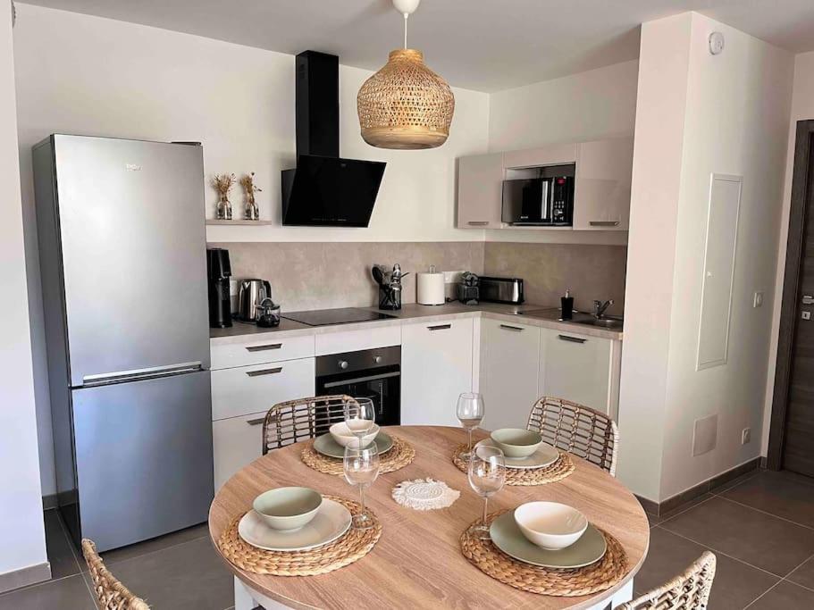 a kitchen with a table with chairs and a refrigerator at Un havre de paix entre mer et montagne à Sant'Ambroggio in Lumio