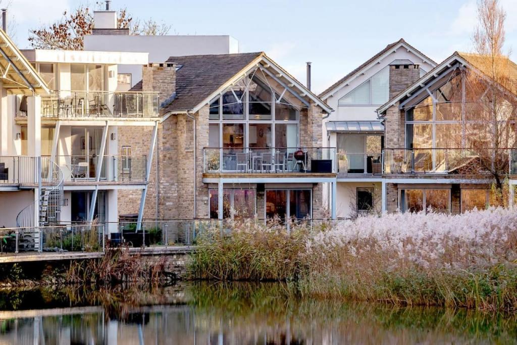 a house next to a body of water at Pennyroyal Lodge HM31 Lakeside Spa Property in Somerford Keynes