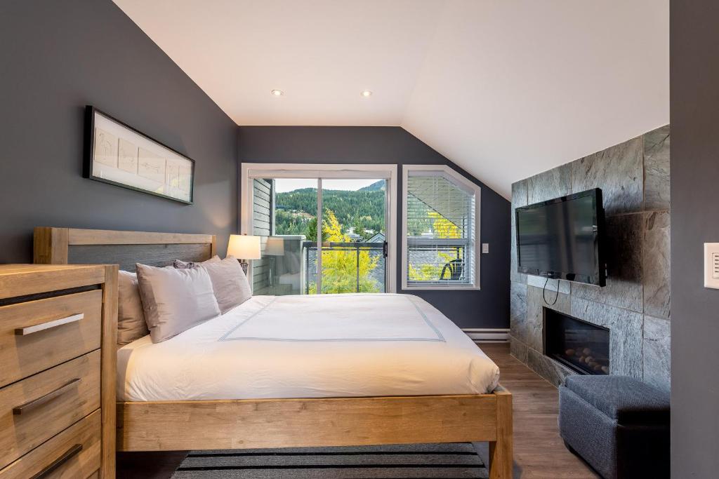 een slaapkamer met een groot bed en een open haard bij Renovated Lynx Property - Spacious 4 bedroom with private balcony and hot tub! in Whistler