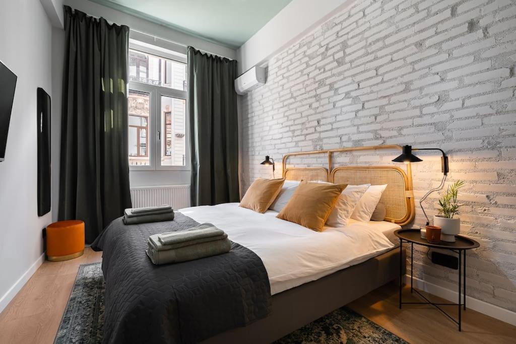 a bedroom with a large bed with a brick wall at Old City Apartment in Bucharest
