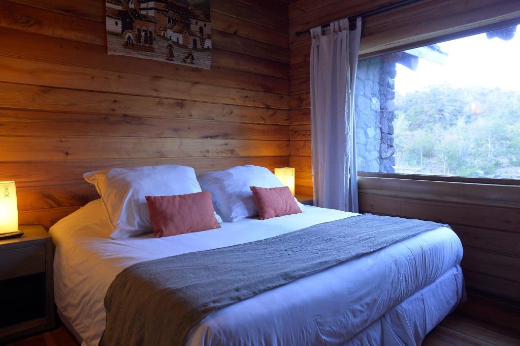 a bedroom with a bed with a window in it at Patagonia Lodge in Las Trancas