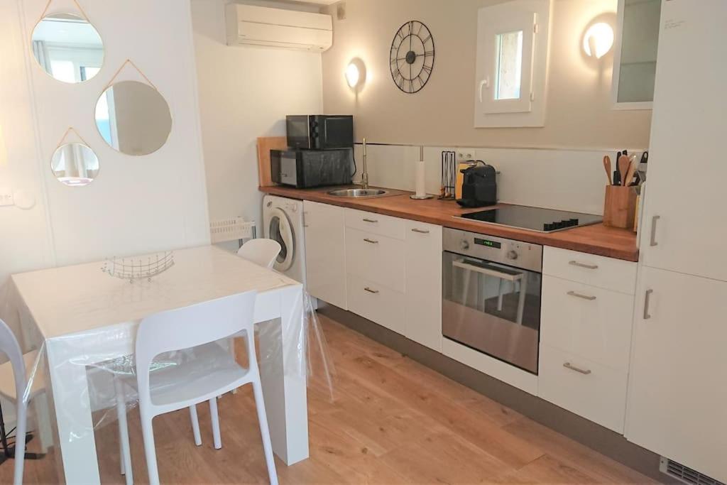 une cuisine avec des armoires blanches, une table et un micro-ondes dans l'établissement Mazet Font Mourier- Gassin_Golfe de Saint-Tropez, à Gassin