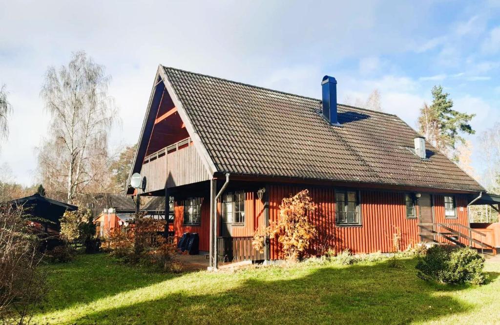 a red house with a black roof on a yard at Vakantiewoning in Småland Zuid-Zweden in Hjältevad