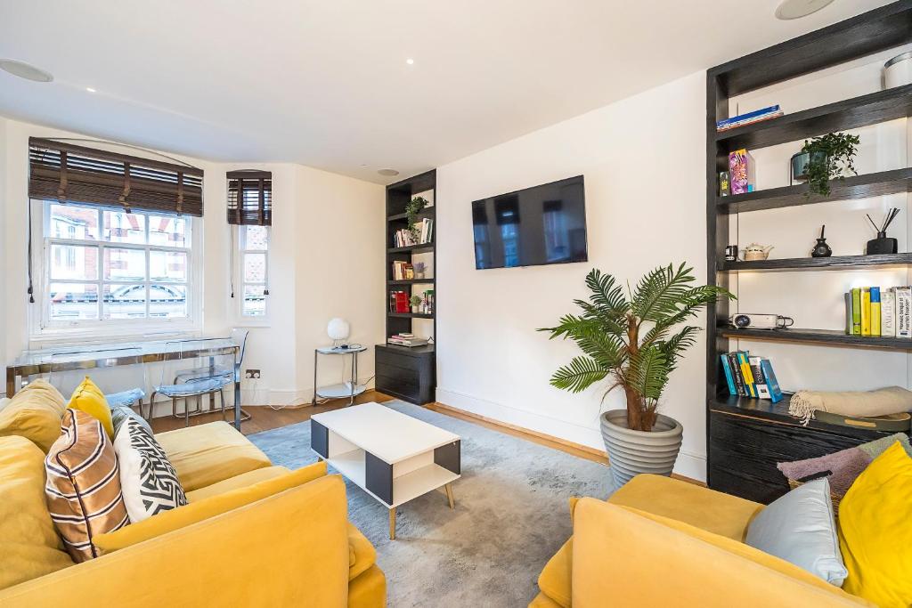 a living room with two yellow couches and a table at Lux Duplex near Oxford St in London