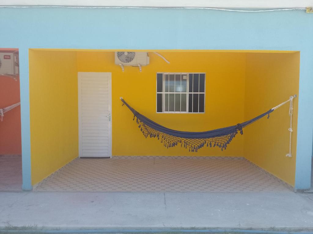 um quarto com uma parede amarela com uma rede de descanso em Casa morada da praia 5 em Peroba