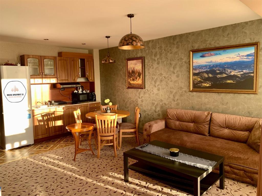 ein Wohnzimmer mit einem Sofa und einem Tisch sowie eine Küche in der Unterkunft Deluxe Apartment 33 Mountain Lodge Pamporovo in Pamporowo