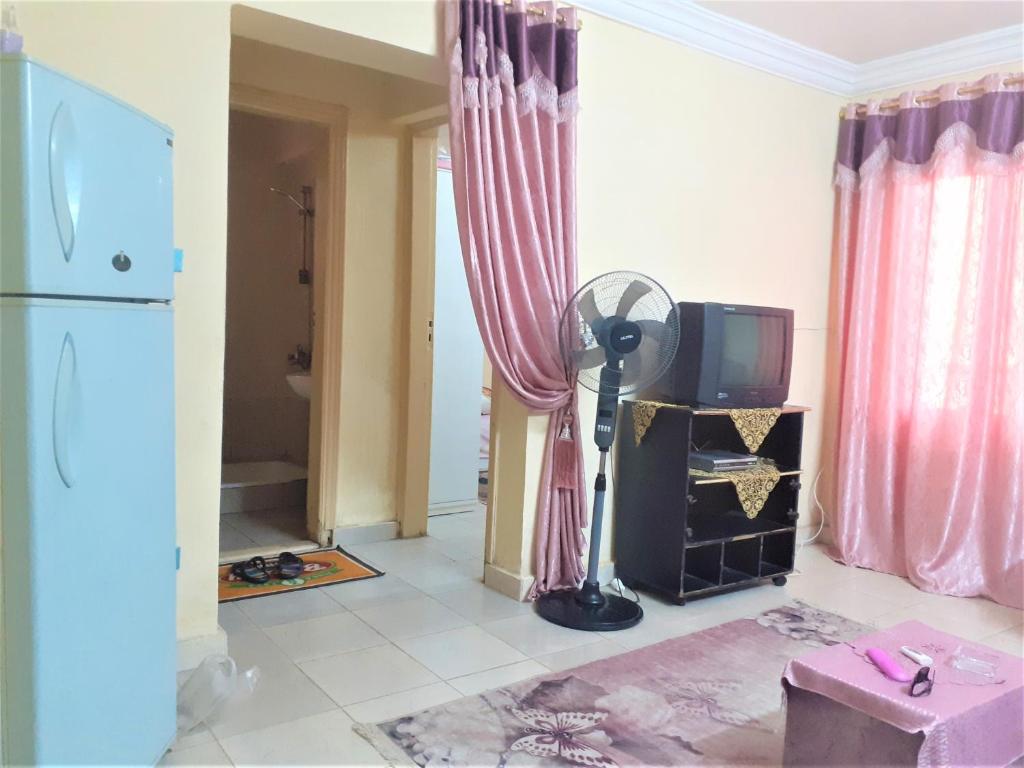 a living room with a tv and pink curtains at Furnished Apartment in Minya