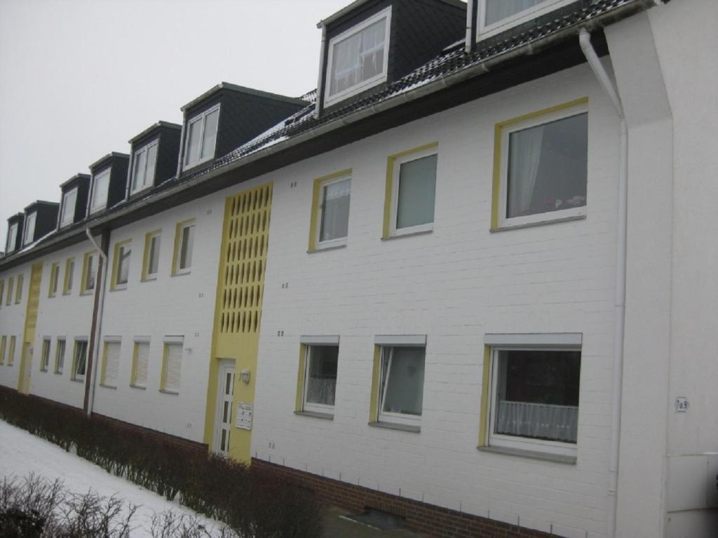 eine Reihe weißer Gebäude mit gelben Fenstern in der Unterkunft Ernst-Gock Weg 07 in Duhnen
