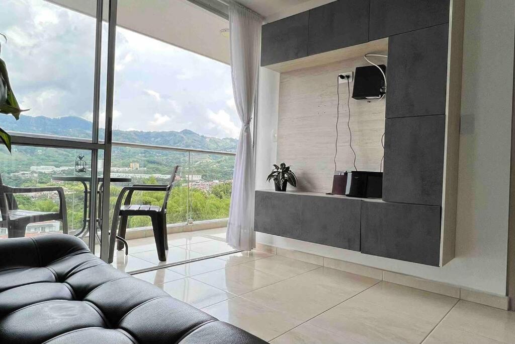 a living room with a couch and a large window at Apartamento nuevo, central, hermosa vista. in Dosquebradas