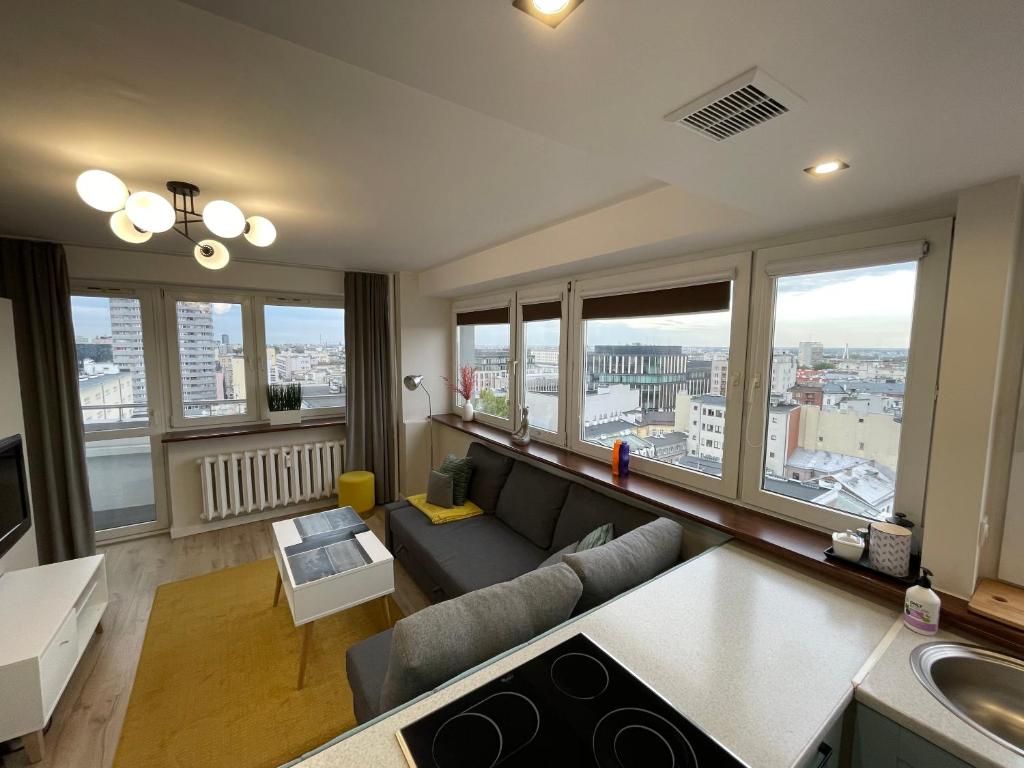 a living room with a couch and some windows at ComeWa Apartments in Warsaw