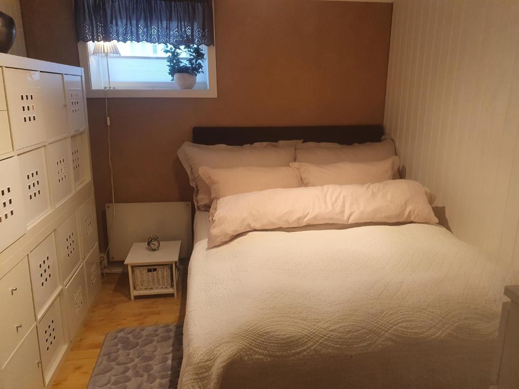 un letto con lenzuola bianche e una finestra in una stanza di Koselig rom med stue i Bodø sentrum a Bodø