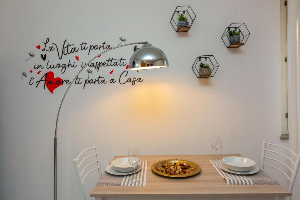 a dining room with a table with a sign on the wall at HappyHouse MI MPX a 7 min da MXP in Busto Arsizio