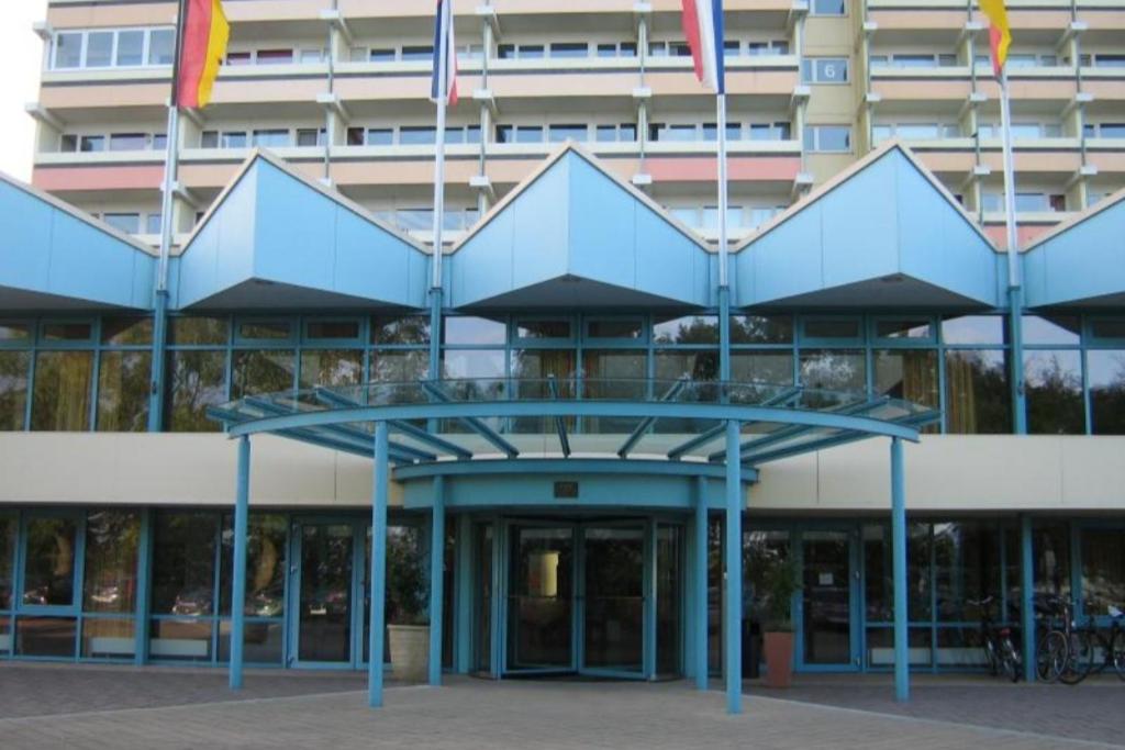un edificio azul con banderas delante en Ferienappartement K1014 für 2 Personen mit Meerblick, en Schönberg in Holstein