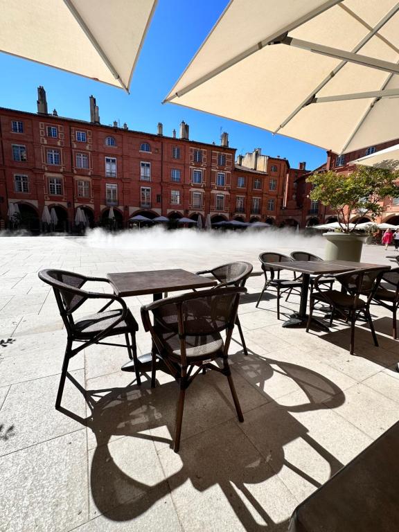 un groupe de tables et de chaises avec parasols dans l'établissement Charmant Studio 1- Hyper centre - Cœur de Montauban-Tous Commerces à pied, à Montauban