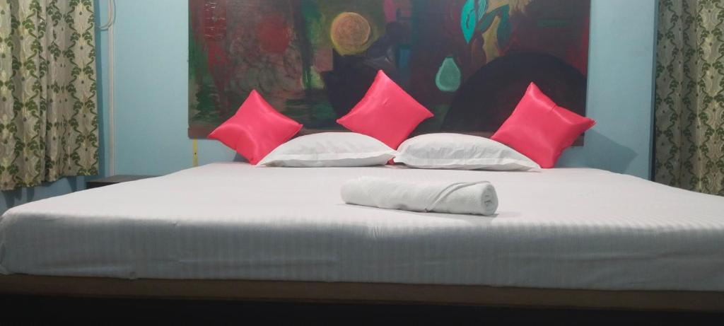 Una cama con almohadas rosas y blancas. en Blue Cherry Guest House en Calcuta