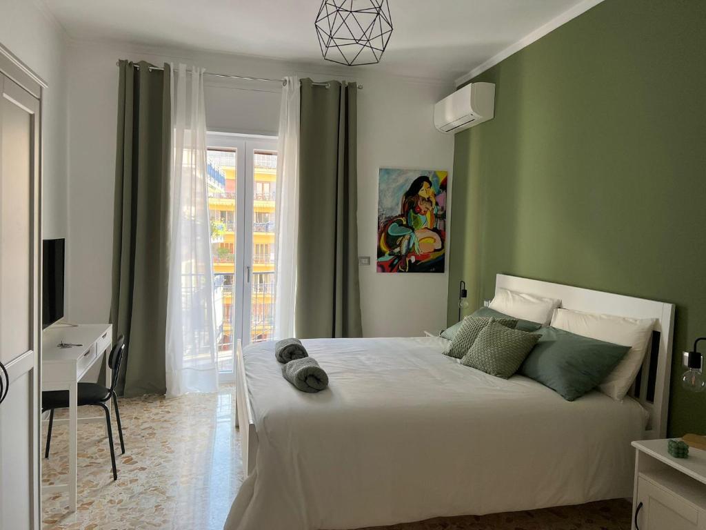 una camera da letto con un letto bianco e pareti verdi di La Veronica Apartment a Napoli