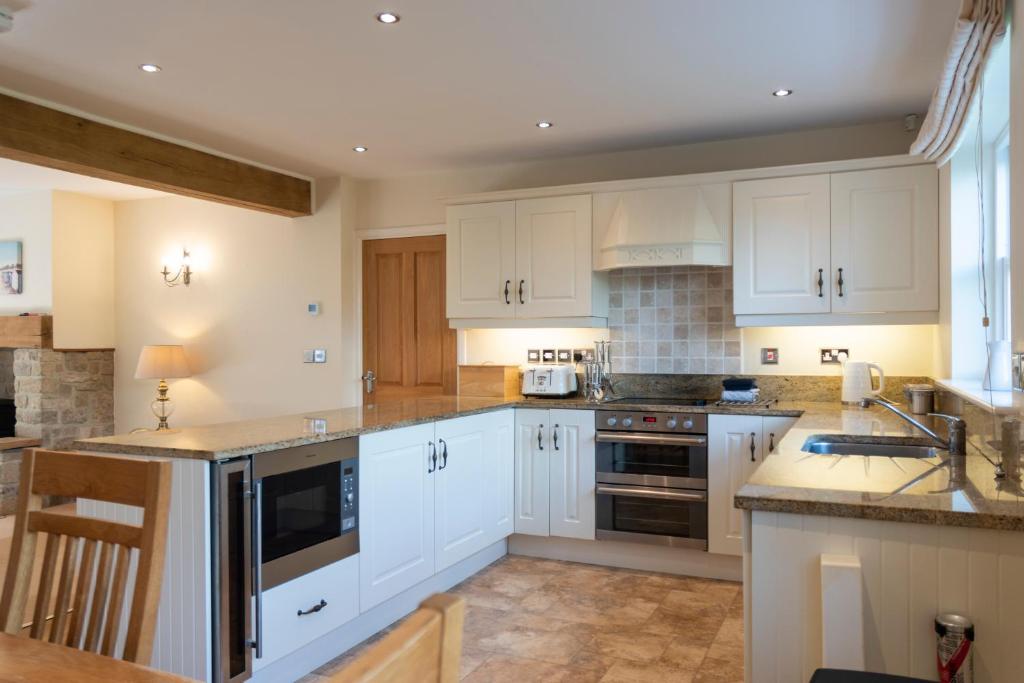 a kitchen with white cabinets and a sink at Lake Cottage , Middleton Hall Estate in Smeafield