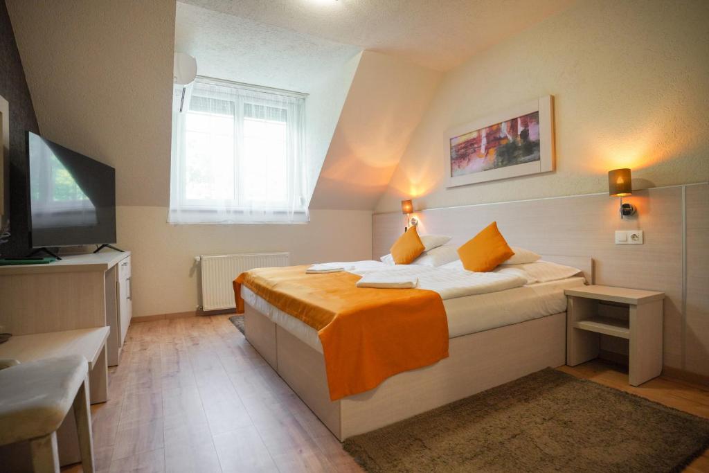 een slaapkamer met een bed met oranje lakens en een televisie bij Szalajka Fogadó és Étterem in Szilvásvárad