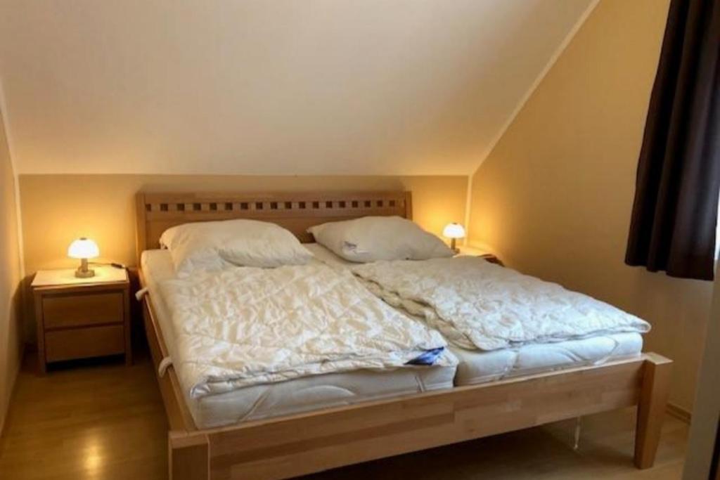 um quarto com uma cama com duas mesas de cabeceira e dois candeeiros em Jacobihof Haus 15 Wohnung 03 em Dahme