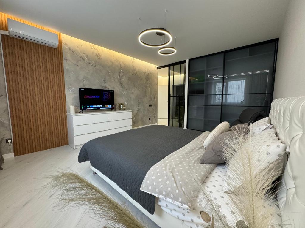 una camera con un grande letto e una TV a parete di Квартира на Подолье a Vinnycja