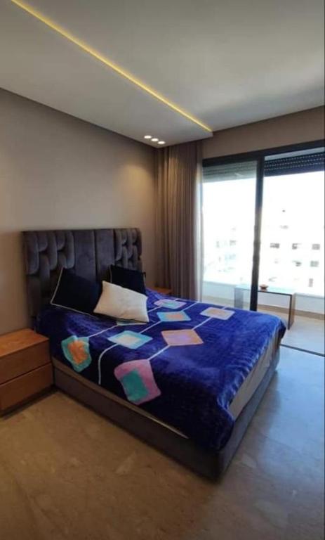 1 dormitorio con 1 cama con edredón azul y ventana en Dar el yousser, en Casablanca