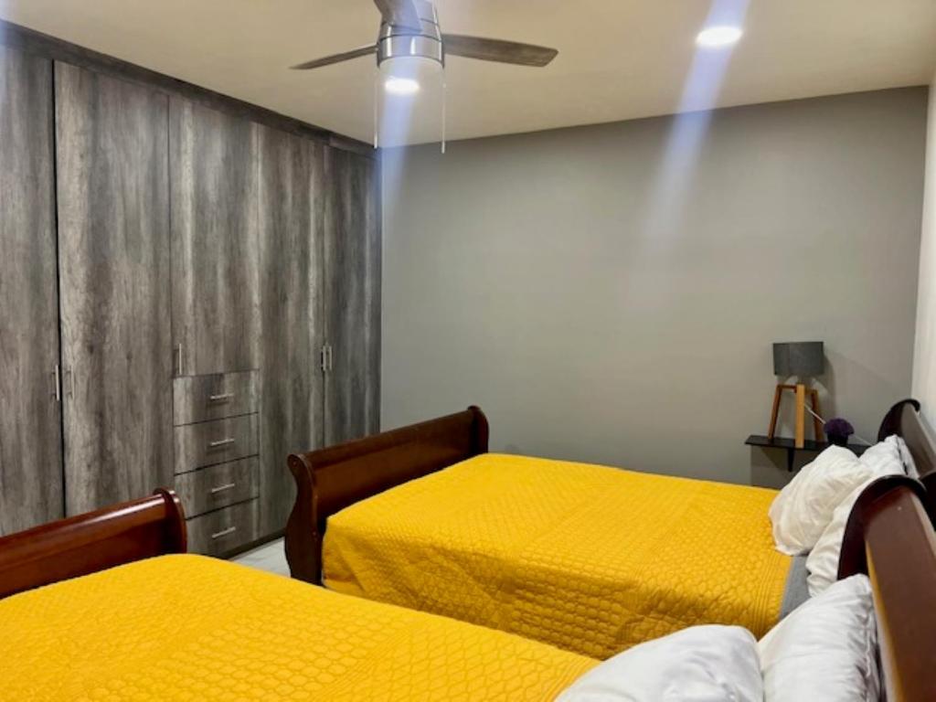 duas camas num quarto com lençóis amarelos em DEPARTAMENTOS ARTICULO 123 - departamento #1 em Tijuana