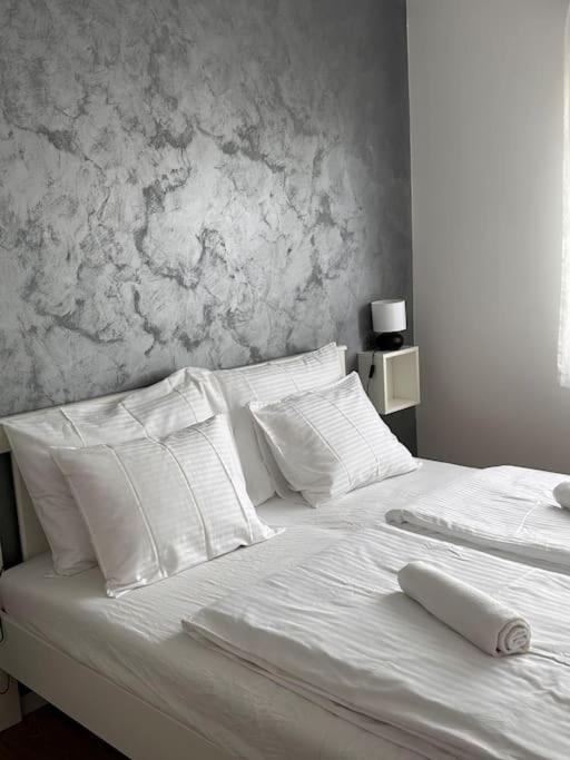 a white bed with white pillows and a wall at Apartman Trsat in Rijeka