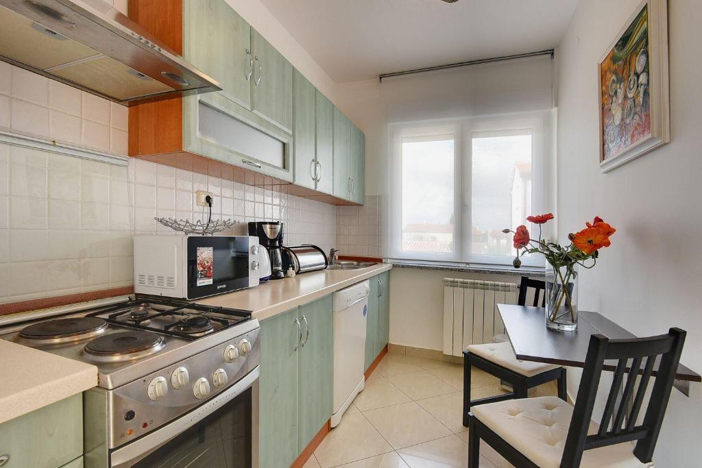 kuchnia z zielonymi szafkami, stołem i kuchenką w obiekcie Attraktive Ferienwohnung mit großem Pool, Klimaanlage, WLAN, BBQ und nur 700 Meter bis zum Sandstrand w Medulinie