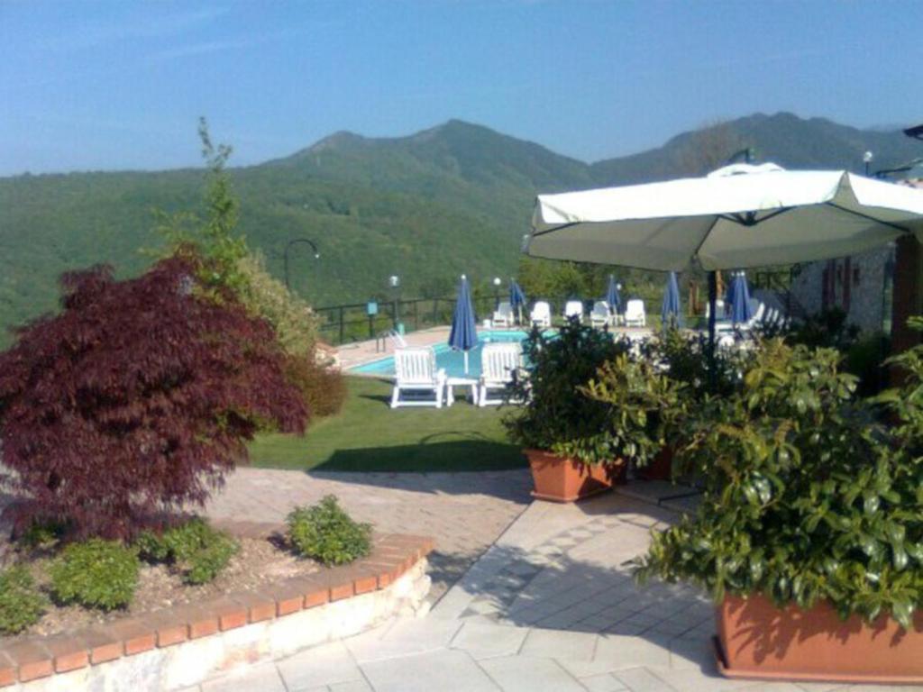 un patio con ombrellone, sedie e piscina di Ferienhäuschen CLAUDIO mit Pool in Tignale a Olzano