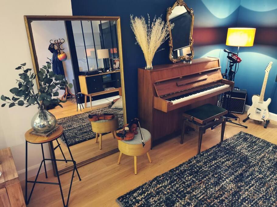 uma sala de estar com um piano e um espelho em Standing, calm & confort. em Bègles