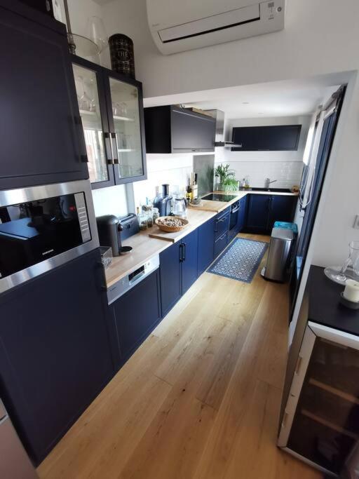 a kitchen with blue cabinets and a wooden floor at Standing, calm &amp; confort. in Bègles