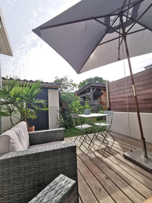 a patio with an umbrella and a table and chairs at Standing, calm &amp; confort. in Bègles