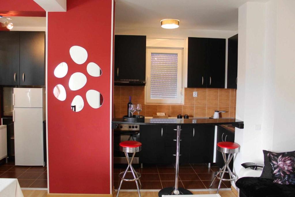 une cuisine avec des armoires noires et un mur rouge dans l'établissement Miss apartman, à Jagodina