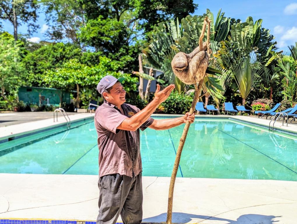 Een man naast een dinosaurus skelet naast een zwembad. bij Puerto Viejo Club, Villa & pool for 6 pax in Puerto Viejo