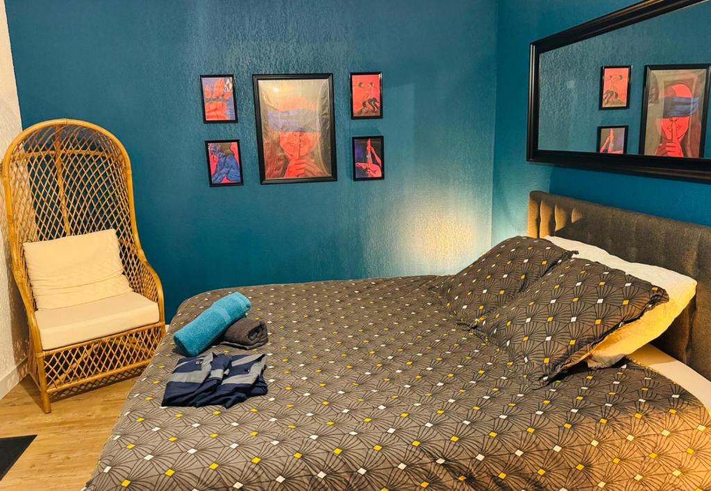 1 dormitorio con 1 cama, 1 silla y pinturas en Secrète loft, en Aucamville