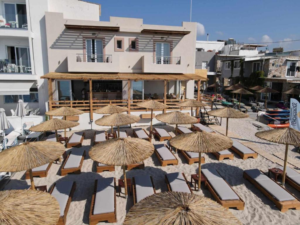 Anna Maria Apartments في كاردامينا: مجموعة من الكراسي والمظلات على الشاطئ