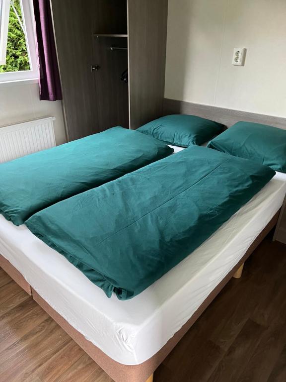 two beds in a room with green sheets and pillows at Chalet de Elina - comfortable chalet for a relaxing stay in Voorthuizen