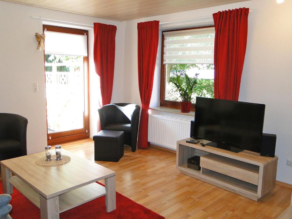 a living room with a television and red curtains at Skrey's To Hus in Kappeln