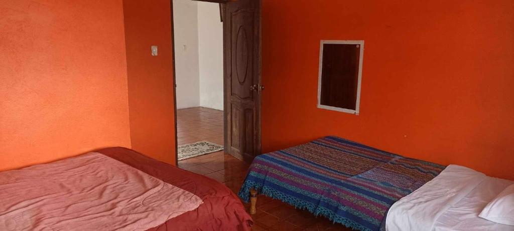 um quarto com 2 camas e uma parede laranja em Intykucha em Otavalo