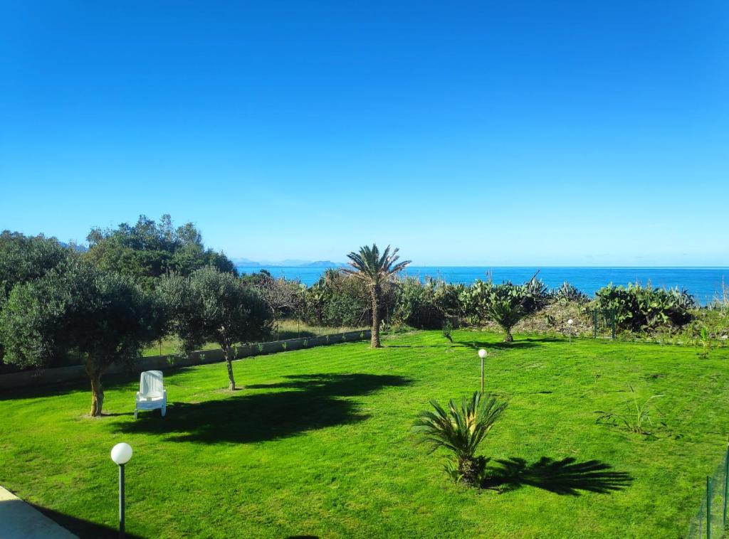 a park with a lawn with a chair and the ocean at Campofelice Holidays in Campofelice di Roccella