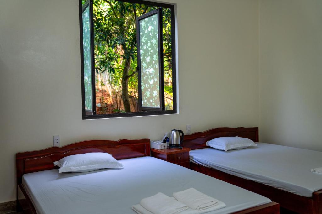 two beds in a room with two windows at Viet Hung Hostel - Motorbikes Rental- BUS TICKET in Làng Lap