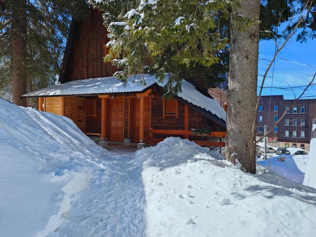 a log cabin in the snow next to a tree at Praška zima in Jahorina