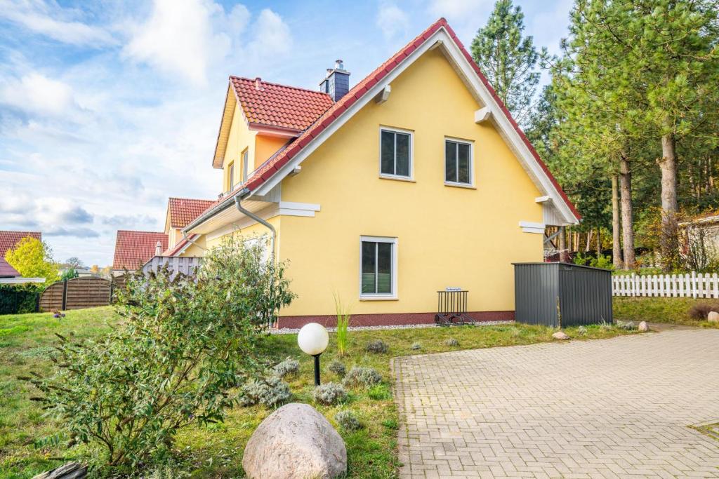 uma casa amarela com um telhado vermelho em charmantes Ferienhaus für 4 Personen mit Sauna und 2 Bädern em Korswandt