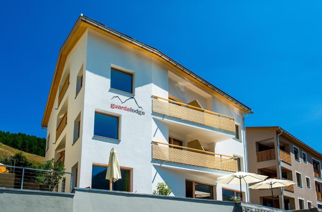 ein weißes Apartmenthaus mit einem Regenschirm und einem Regenschirm in der Unterkunft Guarda Lodge in Guarda