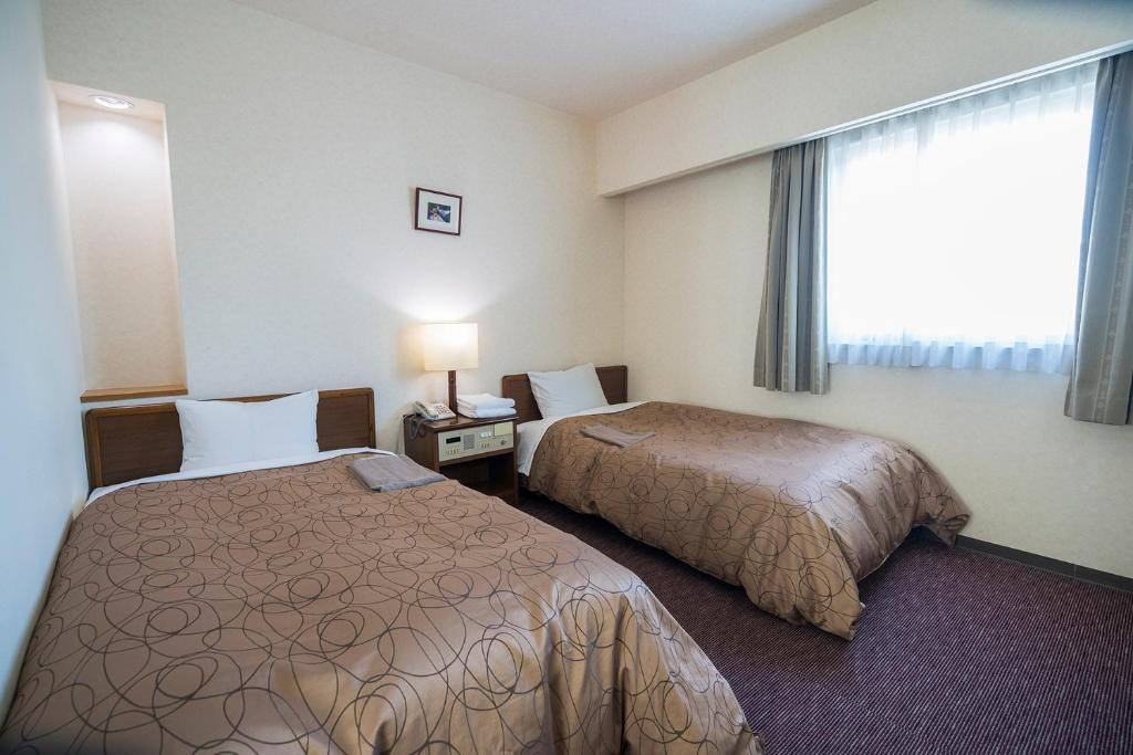 a hotel room with two beds and a window at Minami Fukuoka Green Hotel in Fukuoka